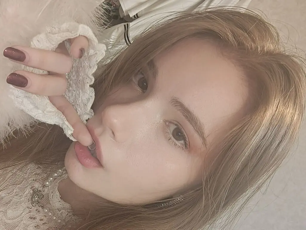 Young woman with long blonde hair wearing a white lace outfit in a soft, dreamy aesthetic mood.