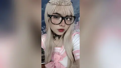 Blonde girl in pink princess outfit and crown wearing black glasses with a dreamy aesthetic.