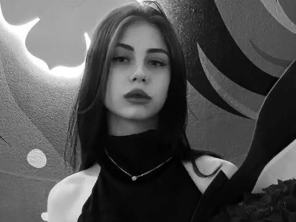 Moody black and white portrait of a young woman in a black turtleneck against a graphic patterned background.