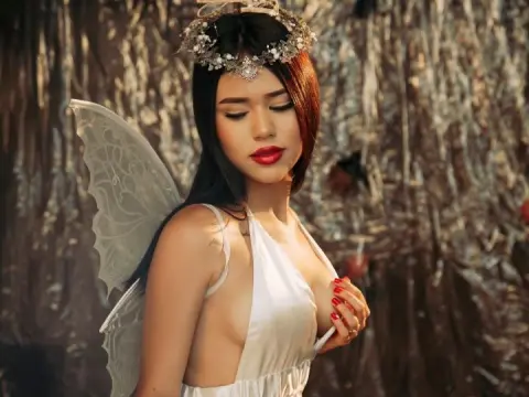 Ethereal fairy woman in a white silk dress and floral crown posing against a shimmering silver background.