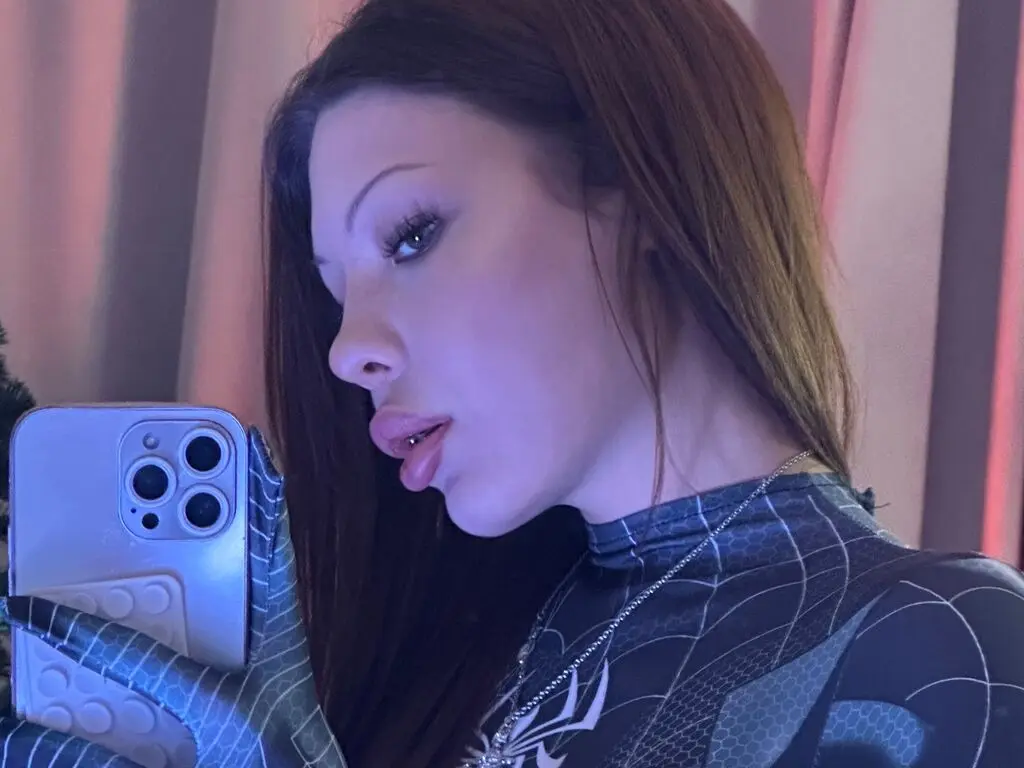 Young woman in a black patterned turtleneck taking a moody selfie in soft indoor lighting.