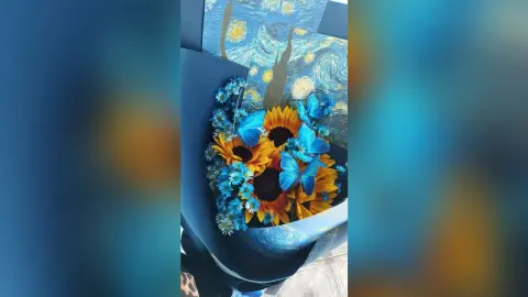 Vibrant sunflower bouquet with bright blue butterfly decorations in a starry night themed gift wrap.
