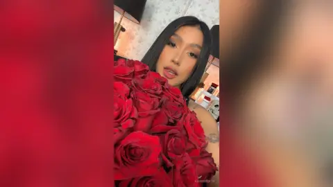 KimRoberth holds a massive bouquet of red roses and smiles at the camera.