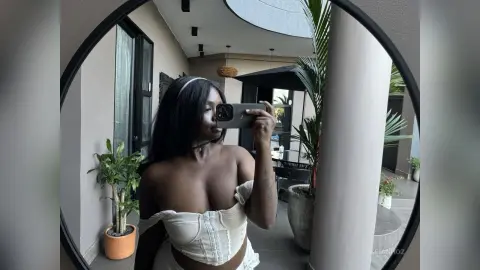 KeianHoz takes a mirror selfie wearing a white corset top, showing her bare shoulders and cleavage.