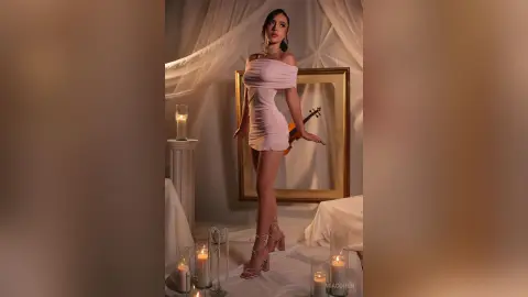Elegant woman in a pink mini dress standing in a romantic candlelit room with a vintage aesthetic.