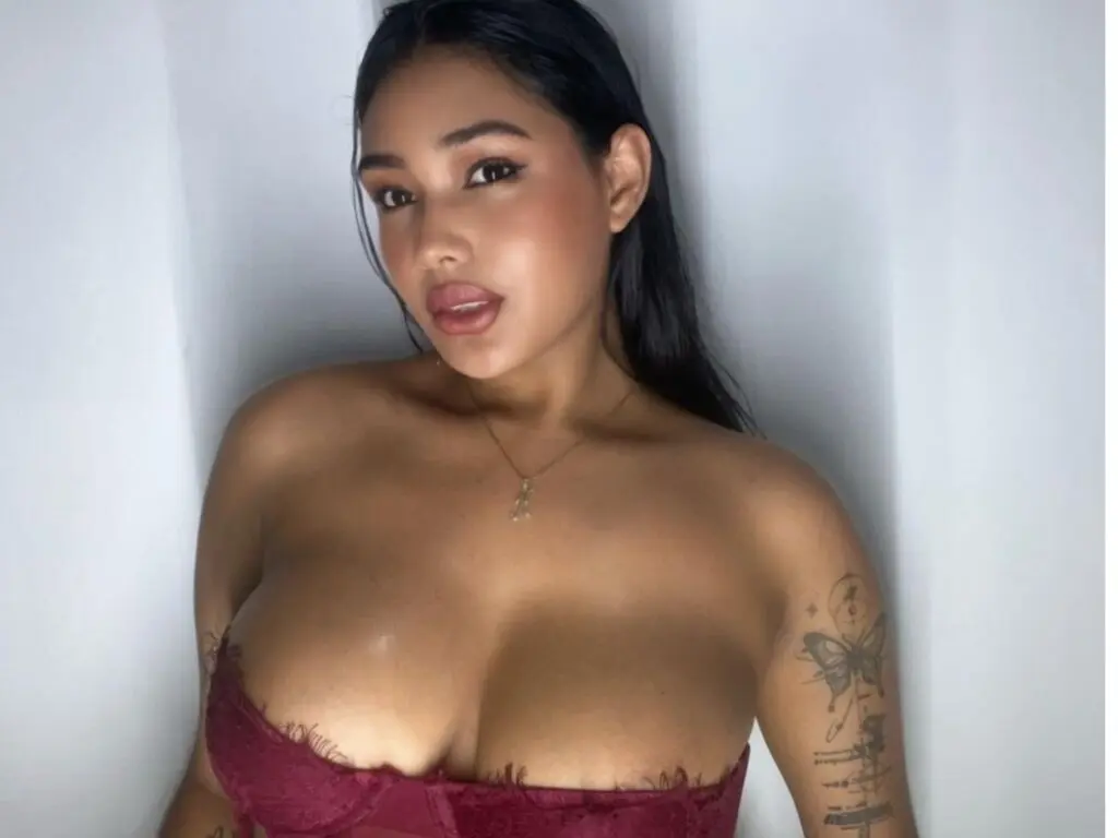 Young woman in a burgundy lace bralette posing against a white background with a soft, intimate mood.