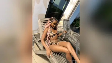 Stylish woman in leopard print bikini relaxing on a patio lounge chair on a sunny day.