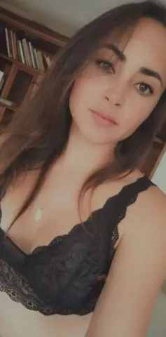 Young woman in a black lace bralette relaxing in a cozy indoor setting with a soft, natural mood.