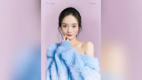 Elegant woman in a cozy blue fuzzy sweater posing against a soft purple background with a dreamy mood.