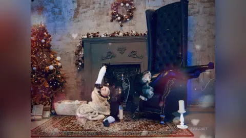 AvaLindt reclines in a high-back black chair wearing black stockings and a dark outfit, posed near a lit Christmas tree and fireplace.