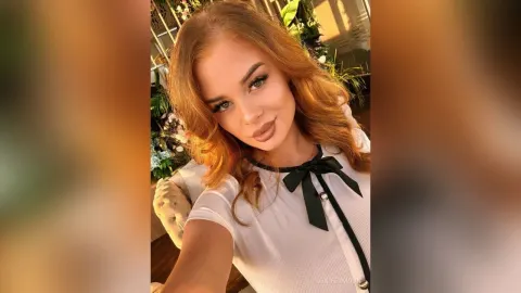 JeniferMoon — JeniferMoon smiles in a white short-sleeved blouse with a black bow detail.