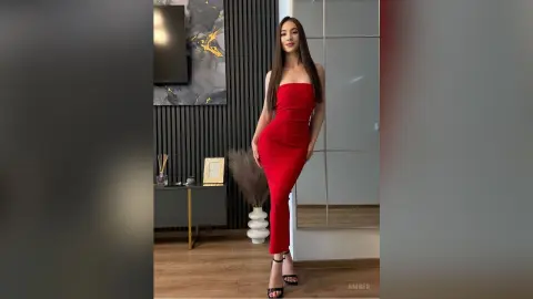 Elegant woman in a sleek red bodycon dress posing in a modern minimalist living room.