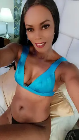 Beautiful woman in a bright blue bikini top relaxing on a bed in a bright bedroom.
