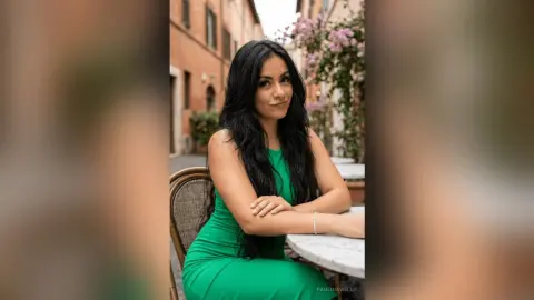 Smiling woman in a green dress sitting at an outdoor cafe in a European city street.
