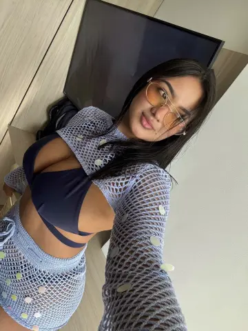 Young woman in a blue crochet bikini and mesh cover-up posing in a modern room.