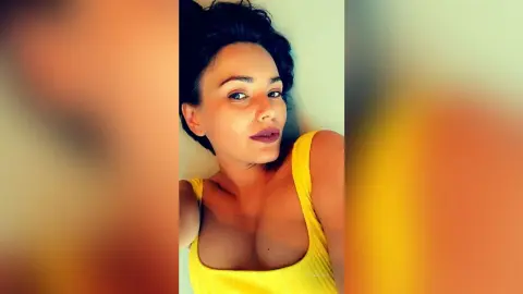 Young woman in a yellow ribbed tank top relaxing indoors with a serene expression.