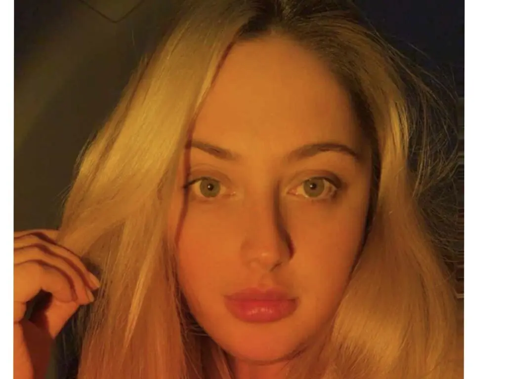 Close-up portrait of a blonde woman with a soft, warm glow in a moody indoor setting.