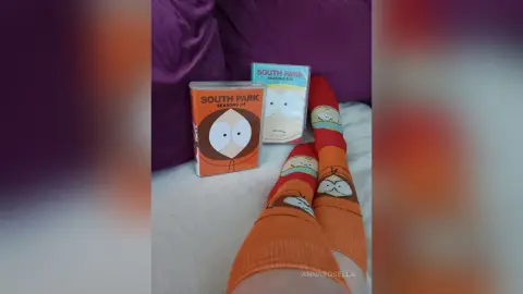 South Park character socks resting next to cartoon DVD box sets on a white bedsheet.