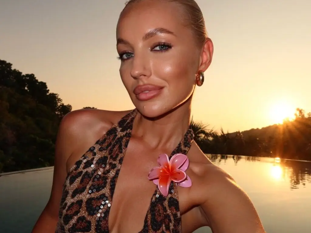 Glamorous woman in a leopard print sequin dress enjoying a sunset glow by a luxury poolside.