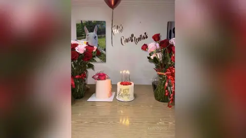 Celebration setup with a birthday cake, red roses, and festive decor on a wooden table.