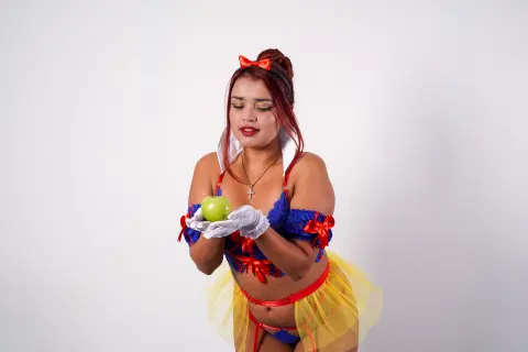 Woman in Snow White cosplay costume holding a green apple against a white background.
