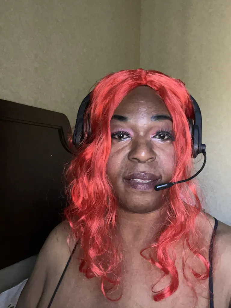 BigVickie smiling at the camera with long, wavy black hair and pink eyeshadow.