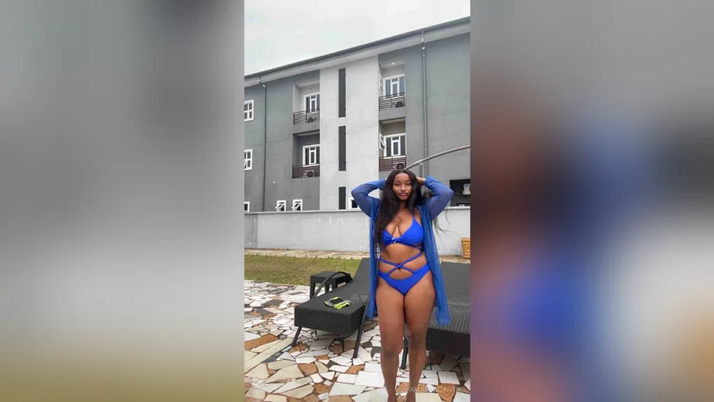 AmandaCaIvin — AmandaCaIvin stands outdoors in a blue bikini and matching cover-up, posing with her hands behind her head.