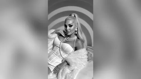 Glamorous woman in a white corset and pearl necklace posing in a stylish monochrome setting.