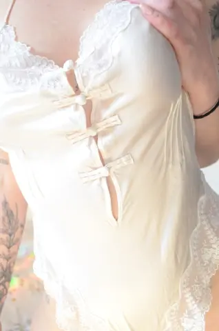 Woman in elegant cream silk and lace lingerie camisole for romantic loungewear.