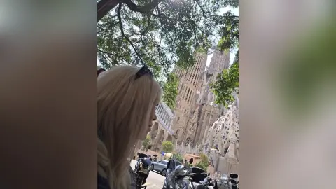 Blonde woman looking at the Sagrada Familia cathedral in Barcelona on a bright sunny day.