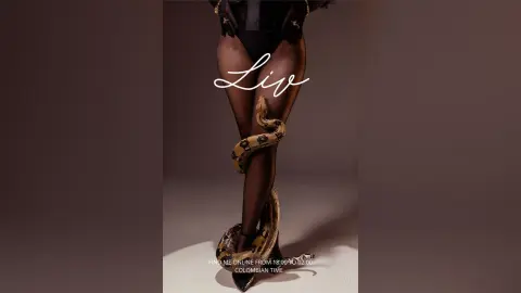 Model in black bodysuit with a large snake wrapped around legs in a minimalist studio setting.