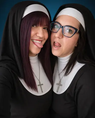 Sinfulmarkedqueens and her friend pose in nun outfits with black veils and silver cross necklaces, sticking their tongues out at the camera.
