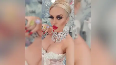 Glamorous woman with dramatic eyelashes and red lips wearing a sparkling silver statement necklace.