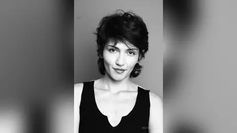 IveteDurand looks directly at the camera with a slight smile, wearing a black tank top against a plain grey background.