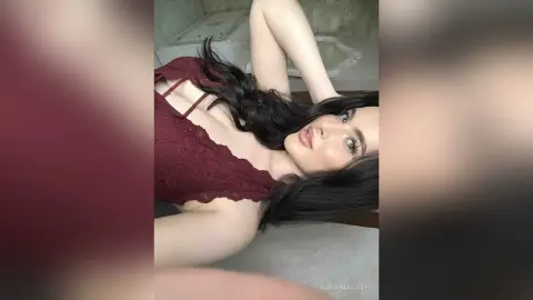 Beautiful brunette woman in a burgundy lace camisole relaxing in a bright, cozy indoor setting.