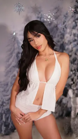 Young woman in a white halter romper posing against a dreamy winter snowflake background.