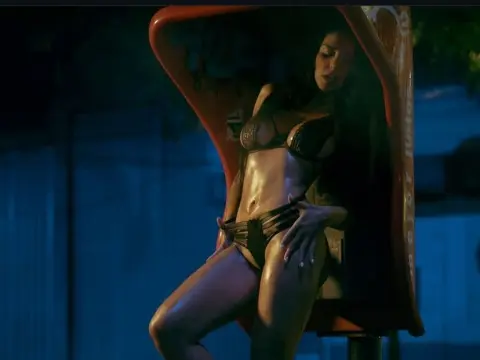 Fit woman in black bikini posing inside a red vintage phone booth at night under moody blue lighting.