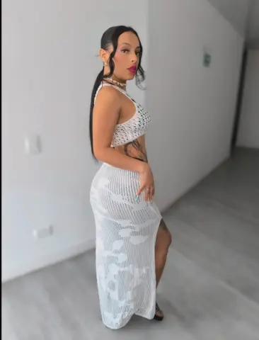 Stylish woman in a white crochet two-piece outfit posing in a bright, minimalist modern room.