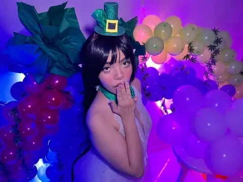 maaeve_elf — Cosplayer in a green leprechaun hat and white dress posing amidst colorful balloons in a magical mood.