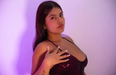 Young woman in a sparkly burgundy sequin top posing against a soft purple background with a moody aesthetic.