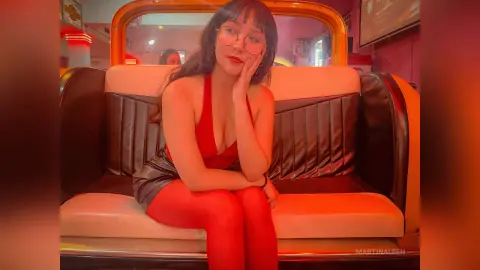 Young woman in a red halter top and red tights sitting on a vintage cream leather booth in a warm cafe.
