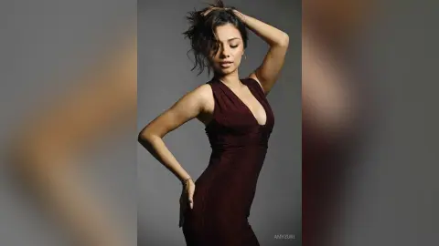 Elegant woman in a sleek burgundy cocktail dress posing against a minimalist studio background.