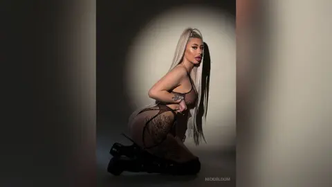 ViviAnne — NickiBloom poses in black sheer lingerie and high heels against a dark background.