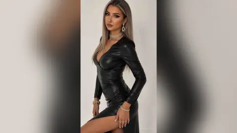 Elegant woman in a sleek black long-sleeve midi dress and gold jewelry posing against a white studio background.