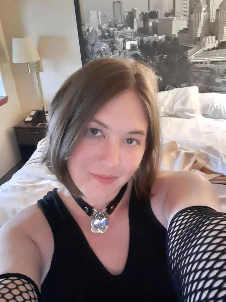 JassieJak looks directly into the camera with a neutral expression, showing her face and long, light-brown hair.