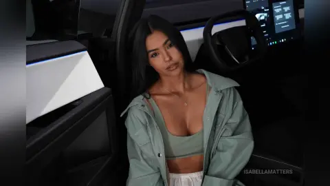 Young woman in a sage green jacket and crop top sitting inside a modern car with a moody aesthetic.