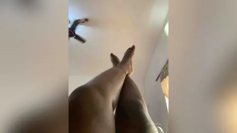 Low angle view of bare legs and feet resting in a relaxed indoor setting.
