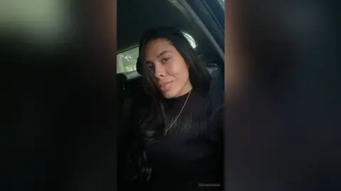 Smiling young woman in a black ribbed turtleneck sitting in a car during golden hour.