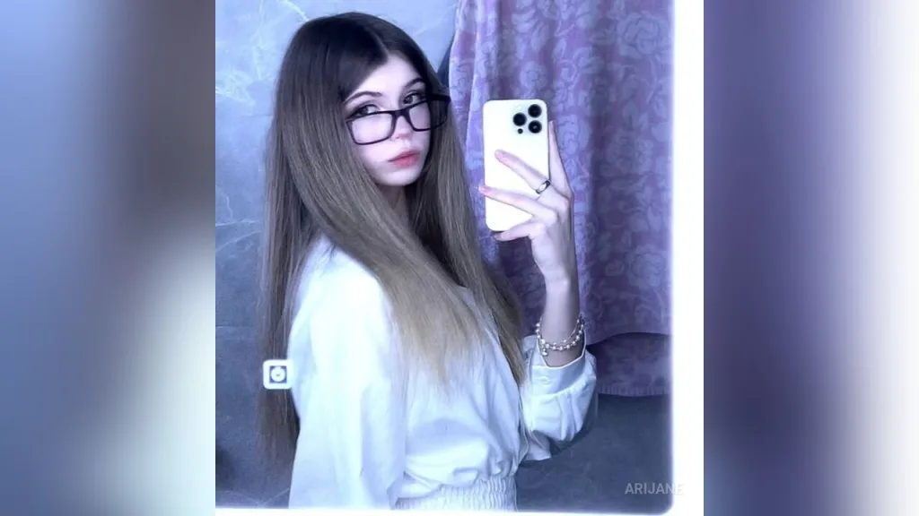 Young woman with long blonde hair taking a mirror selfie in a black turtleneck sweater.