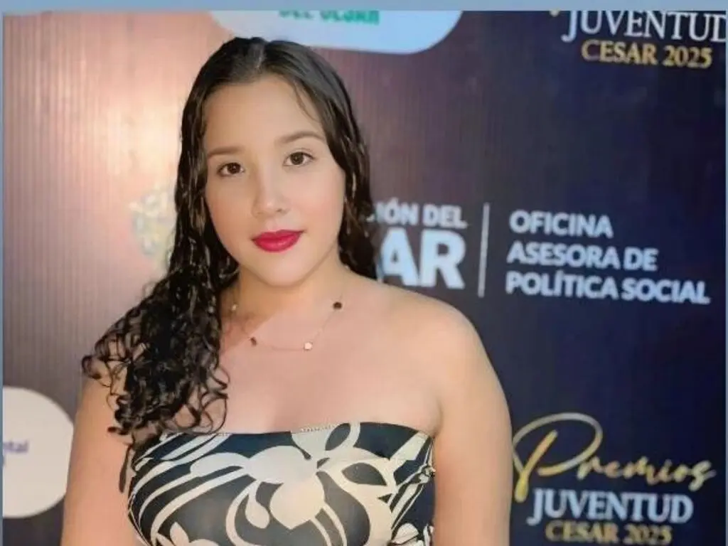 Young woman in a black and white floral strapless top smiling at a Juventud Cesar 2025 event.
